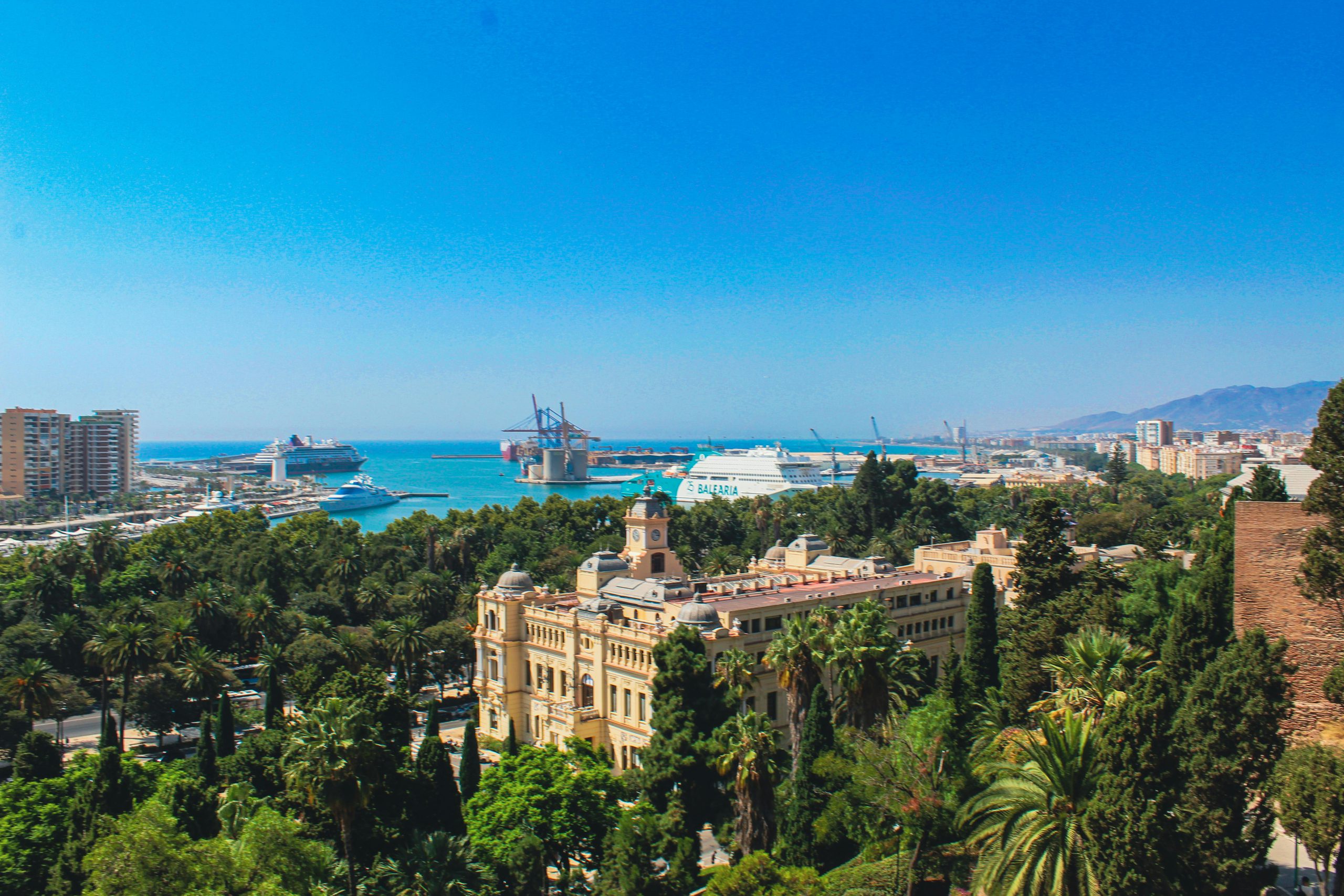 Breathtaking aerial view of Málaga, Spain featuring the bustling port and lush greenery.